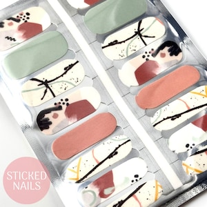 May include: A pack of nail polish wraps with abstract designs in shades of green, brown, and white. The pack is labelled "STICKED NAILS".