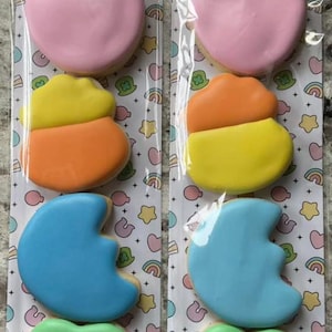 Könnte beinhalten: Zwei Packungen Lucky Charms Kekse. Jede Packung enthält ein rosa Herz, einen orange-gelben Candy Corn, einen blauen Halbmond und ein grünes Kleeblatt. Die Packungen haben eine Überschrift mit der Aufschrift "Lucky Charms" in grünen Buchstaben.
