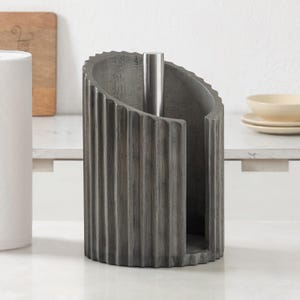 Peut inclure: Un porte-essuie-tout cylindrique dot&eacute; d'un ext&eacute;rieur gris fonc&eacute; cannel&eacute; avec une texture verticale. Le support poss&egrave;de une tige centrale en m&eacute;tal argent&eacute; lisse s'&eacute;levant depuis la base pour maintenir un rouleau d'essuie-tout en place.