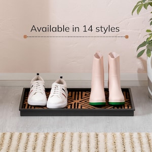 May include: A rectangular black boot tray with a textured brown and black geometric patterned insert. The tray holds a pair of white sneakers with red and blue side stripes and a pair of light pink rain boots with green soles. Text reads Available in 14 styles.