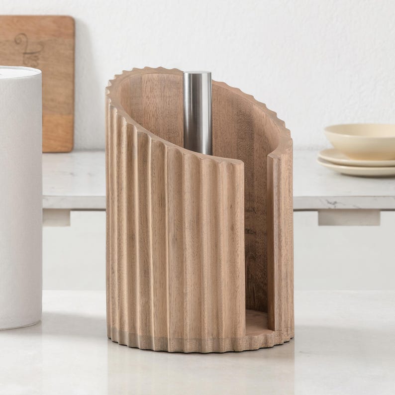 Peut inclure: Un porte-essuie-tout cylindrique en bois brun clair avec une texture cannel&eacute;e verticale. Le support comporte une tige centrale verticale en acier inoxydable et une ouverture incurv&eacute;e sur un c&ocirc;t&eacute; pour permettre de distribuer le papier.