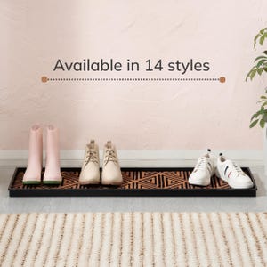 May include: A rectangular black boot tray with a copper-colored geometric pattern insert. The tray holds two light pink boots, two beige lace-up ankle boots, and two white sneakers. The text "Available in 14 styles" is printed above the tray.
