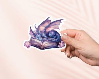 May include: A purple and blue galaxy dragon curled up asleep on top of an open book with pink flowers on either side.