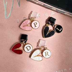 May include: Four heart-shaped charms with gold-tone edges, each paired with a small circular pendant featuring a gold letter. The set includes a pink heart with letter P, a black heart with letter L, a red heart with letter D, and a white heart with letter R.