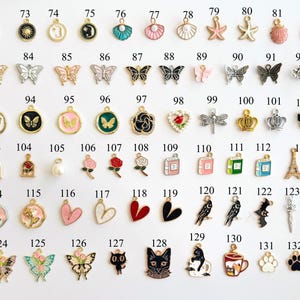 May include: A collection of small, decorative charms in various shapes and colors. The charms include butterflies, hearts, flowers, animals, and other designs. They are likely used for jewelry making or crafting.