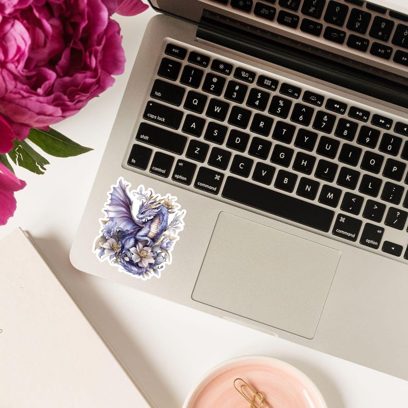 May include: A sticker featuring a purple dragon with gold accents, surrounded by white flowers. The dragon is depicted with wings spread and a gentle expression.