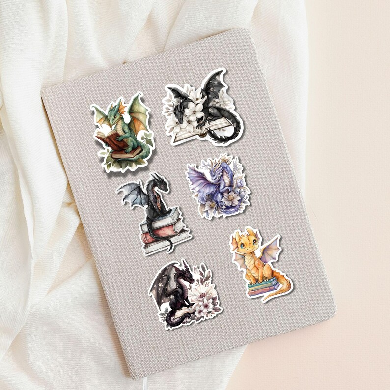 May include: Six colorful stickers featuring dragons reading books. Each sticker has a different dragon with a unique color scheme and pose. The dragons are sitting on stacks of books with flowers and leaves around them.