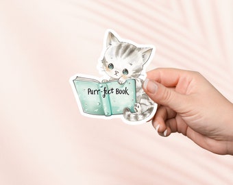 May include: A sticker featuring a cartoon cat reading a book. The cat is gray and white with big blue eyes. The book is teal with the words "Purr-fect Book" written on it.