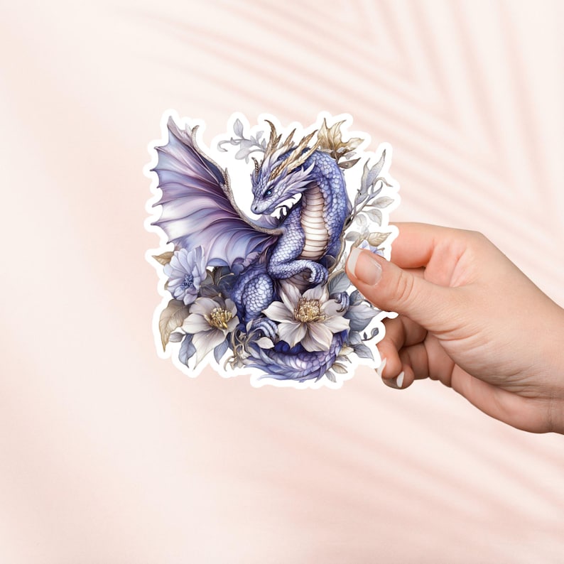 May include: A purple dragon with gold accents is nestled in a bed of white and purple flowers. The dragon has its wings spread out and is looking to the side. The flowers are in full bloom and have delicate petals.