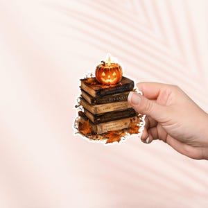 Peut inclure: Un autocollant découpé représentant une pile de cinq livres au style ancien surmontée d'une citrouille illuminée. Les livres sont entourés de feuilles d'automne orange et brunes. Les titres visibles incluent Piranesi, The Invisible Life of Addie LaRue et The Secret History.