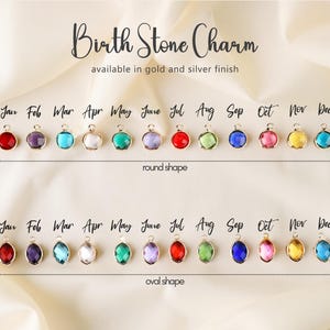 Op de afbeelding: Afbeelding van geboortesteenbedels in ronde en ovale vormen. Elke bedel heeft een andere kleur, die een maand van het jaar vertegenwoordigt. De tekst luidt "Birth Stone Charm" en "available in gold and silver finish".