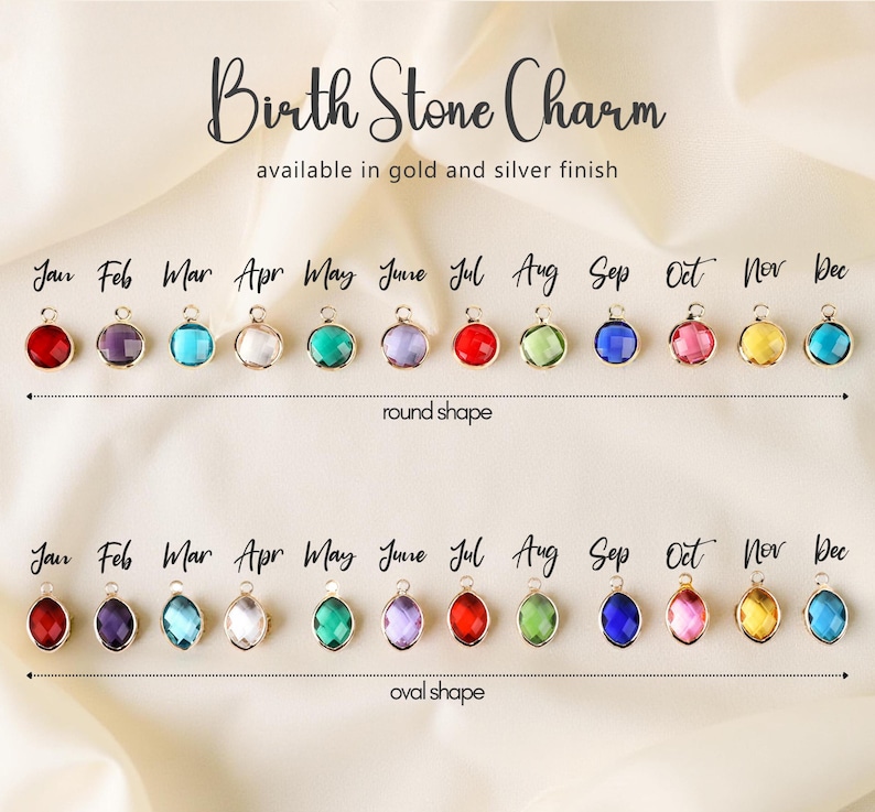 Op de afbeelding: Afbeelding van geboortesteenbedels in ronde en ovale vormen. Elke bedel heeft een andere kleur, die een maand van het jaar vertegenwoordigt. De tekst luidt "Birth Stone Charm" en "available in gold and silver finish".