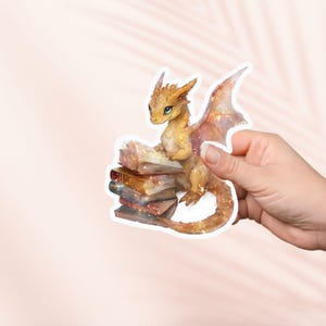Pegatina de libro de dragón bebé dorado, pegatina de vinilo adorable, artículos de fantasía para amantes de los libros, pegatinas para Kindle, amantes de la lectura, Booktok