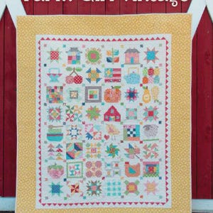 May include: A patchwork quilt titled Farm Girl Vintage by Lori Holt of Bee in my Bonnet, featuring a grid of colourful blocks with various motifs like houses, fruit, and animals, surrounded by a yellow patterned border on a red background.