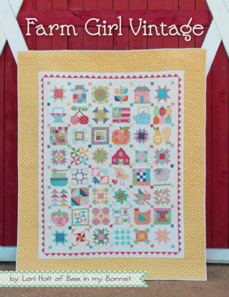 May include: A patchwork quilt titled Farm Girl Vintage by Lori Holt of Bee in my Bonnet, featuring a grid of colourful blocks with various motifs like houses, fruit, and animals, surrounded by a yellow patterned border on a red background.