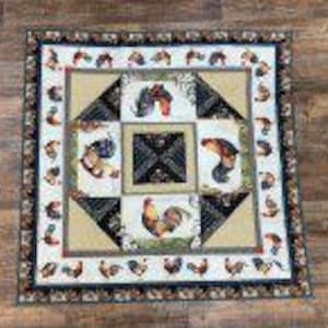 May include: A square quilt featuring a central black square with a white geometric pattern, surrounded by four beige panels each displaying a colorful rooster illustration. The border is white with a repeating pattern of small roosters.