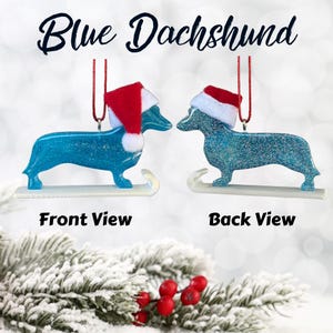 Handmade Dachshund Christmas Ornament made with high quality epoxy resin. The blue ornament comes with a red hanger and white sled with subtle silver glitter highlights on the front and dazzling glitter on the back.