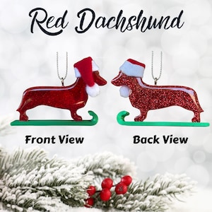 Handmade Dachshund Christmas Ornament made with high quality epoxy resin. The red ornament comes with a silver hanger and green sled with subtle red glitter highlights on the front and dazzling glitter on the back.