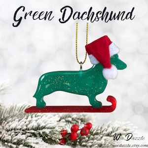 Handmade Dachshund Christmas Ornament made with high quality epoxy resin. The green ornament comes with a gold hanger and red sled with subtle gold glitter highlights on the front and dazzling glitter on the back.