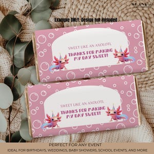 May include: Two pink candy bar wrappers with axolotl illustrations and the text "SWEET LIKE AN AXOLOTL THANKS FOR MAKING MY DAY SWEET!". The wrappers have a bubble pattern and are labeled "Example ONLY. Design not included."