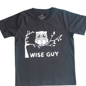 May include: A black t-shirt with a white owl reading a book on a branch. The text "WISE GUY" is printed below the owl.