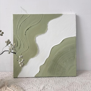 Peut inclure: Une peinture sur toile carrée présentant des couches épaisses et texturées d'empâtement vert sauge et blanc. La composition affiche une division organique et ondulée entre les couleurs, avec une section montrant des crêtes parallèles.