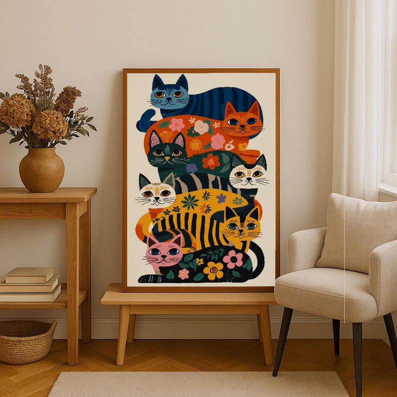May include: A framed art print featuring a stack of stylized cats in various colors and patterns. The cats have floral and striped designs, with a palette of blue, orange, green, yellow, and pink. The artwork is displayed in a room with neutral tones.