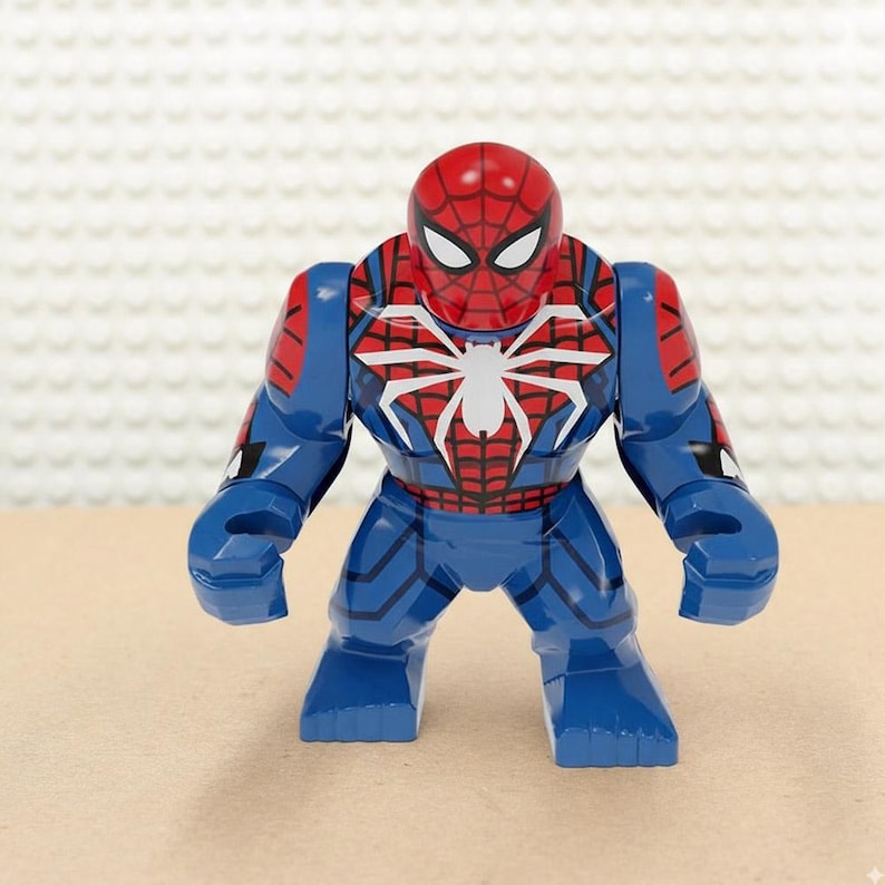 May include: A blue and red Spider-Man action figure. The figure has a red mask with white eyes and a white spider emblem on the chest. The figure is in a standing pose and is made of plastic.