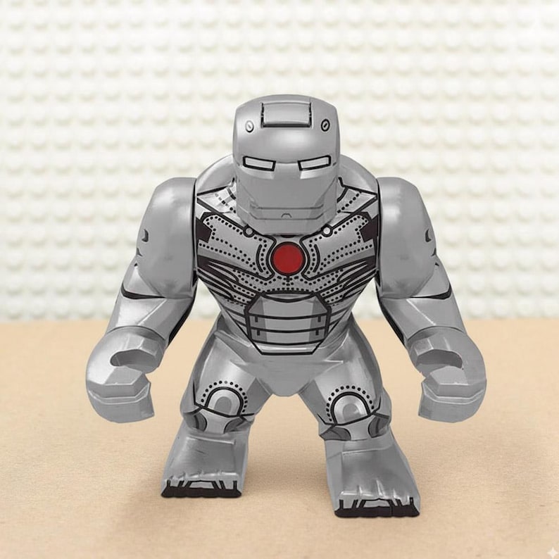 May include: A silver-colored Iron Man action figure with a red circular chest piece. The figure has a detailed design, including lines and dots, and is posed with its arms at its sides. The figure is made of plastic.