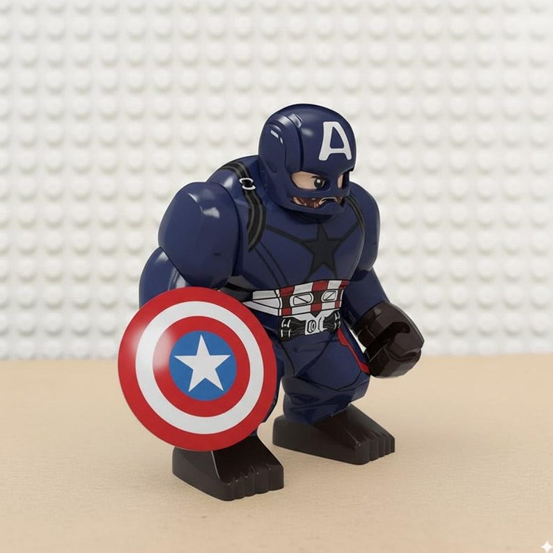 May include: A navy blue Captain America action figure with a white "A" on the helmet and a star on the chest. The figure is holding a red, white, and blue shield with a white star in the centre.