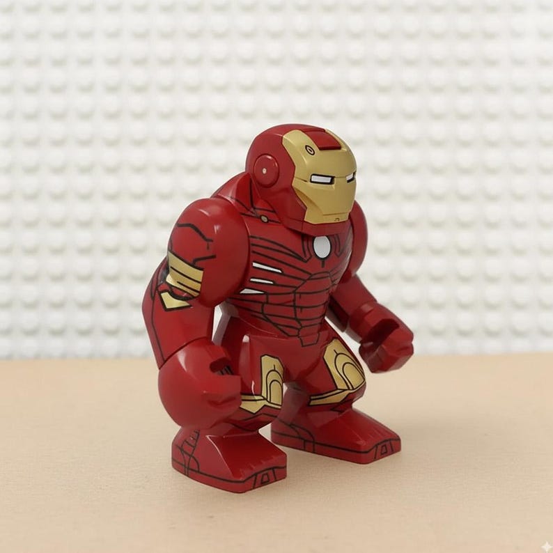May include: A red and gold Iron Man action figure. The figure has a red body with gold accents on the shoulders, arms, and legs. The helmet is red and gold with a rectangular eye opening. The figure is standing on a light brown surface.