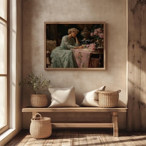 May include: A framed painting depicts a woman in a blue dress seated at a table with pink flowers. Below, a wooden bench holds two white pillows, a woven basket, and a small potted plant. The scene is bathed in warm light.