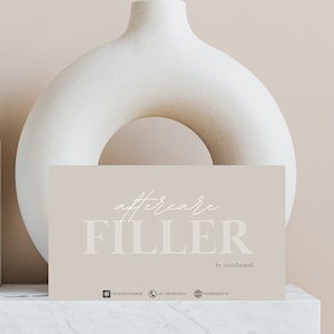 May include: A light brown card with the text "aftercare FILLER by yourbrand" in white. The card is sitting on a white marble surface with a white ceramic vase in the background.