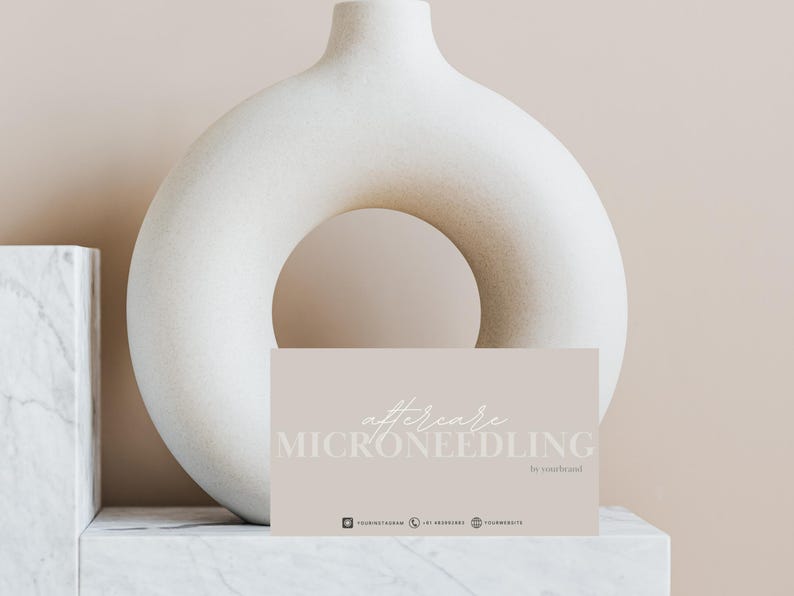 Puede incluir: Una tarjeta de color marr&oacute;n claro con el texto "aftercare MICRONEEDLING by yourbrand" en letra blanca. La tarjeta est&aacute; sobre una superficie de m&aacute;rmol blanco delante de un jarr&oacute;n de cer&aacute;mica blanco.