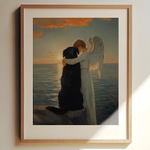 May include: A framed print depicts an angel embracing a black dog, set against a seascape at sunset. The angel, in a white gown with feathered wings, hugs the dog. The artwork is framed in a light-colored wooden frame.