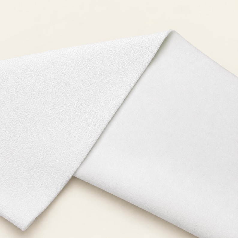 May include: A folded piece of white fabric showing two distinct textures. The top layer features a pebbled, granular surface, while the bottom layer displays a smooth, flat, and uniform weave. The material is bright white throughout the entire piece.