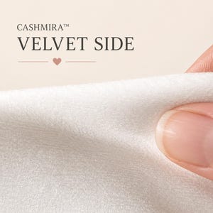 May include: A close-up of white velvet fabric with a soft, dense texture. The text CASHMIRA VELVET SIDE is printed in dark grey above the fabric, accompanied by a small heart icon centred between two horizontal lines, indicating the material surface.