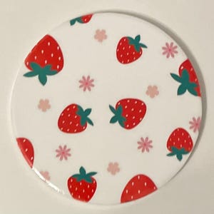 May include: White ceramic coaster with a repeating pattern of red strawberries and pink flowers.