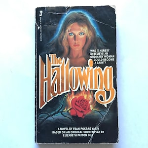 May include: Vintage paperback book titled "The Hallowing." The cover features a woman with long blonde hair and blue eyes, a red rose, and the text "Was it heresy to believe an ordinary woman could become a saint?"