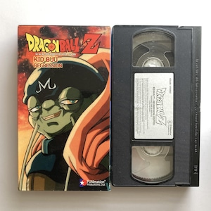 May include: A Dragon Ball Z Kid Buu Regression VHS tape and its cardboard sleeve. The sleeve features a green-skinned character with a black cap and orange cape. The white label on the black plastic cassette displays the title and Funimation logo.