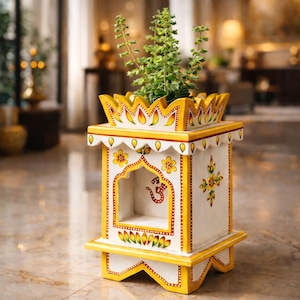 Könnte beinhalten: Ein handbemalter Holzblumentopf in Weiß und Gelb mit einem dekorativen Design. Der Pflanztopf hat eine kronenartige Oberseite und eine kleine bogenförmige Öffnung. Er enthält grüne Pflanzen und ist ein einzigartiger Einrichtungsgegenstand.
