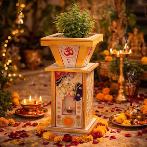 May include: A decorative, tiered wooden planter with a plant on top. The planter is painted yellow and white with red accents and a religious symbol. The base features a painted scene of two figures. The scene is surrounded by candles, flowers, and incense.