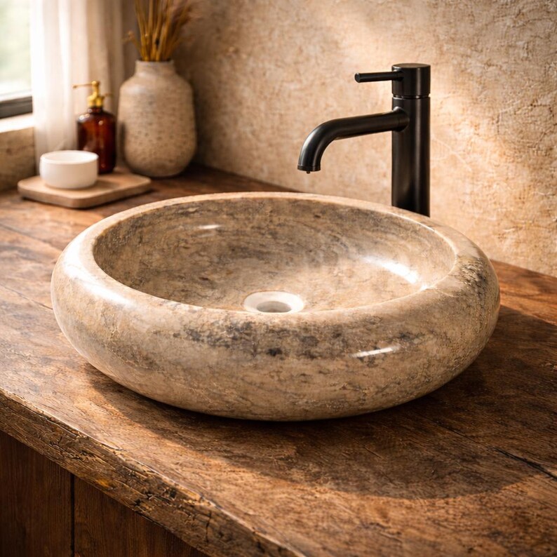 Close-up view of a handcrafted marble vessel sink with a sleek brass faucet, highlighting the natural stone patterns and smooth finish. Ideal for modern bathroom vanities, this designer basin adds a sophisticated and timeless look. Perfect choice for homeowners seeking luxury and durability.