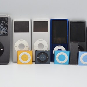 May include: A collection of various iPod models in different sizes and colors. The devices include classic iPods in silver and black, and smaller iPod Shuffles in yellow, black, and blue. The screens and control wheels are visible.