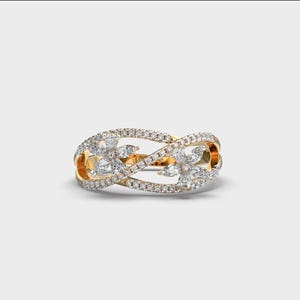 May include: A gold ring with a floral design, encrusted with numerous small, sparkling diamonds. The ring features an interwoven design with two flower-shaped clusters of diamonds, creating a delicate and elegant appearance. The ring is set against a plain white background.