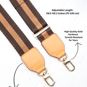 Op de afbeelding: Bruin en beige gestreepte tasriem met goudkleurige hardware. Gemaakt van premium volnerf vachetta leer. Verstelbare lengte van 75-140 cm, breedte 4 cm.