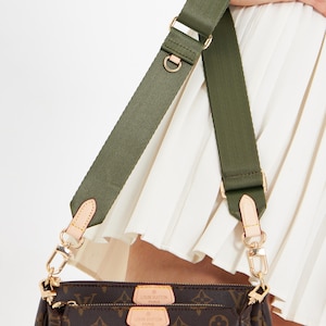 May include: A brown handbag with a monogram pattern, featuring a green strap and gold-colored hardware. The bag has a zipper closure and two small tags. The text "The bag is not for sale" is visible.