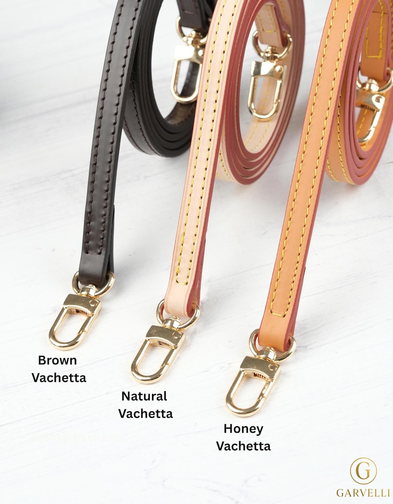 Puede incluir: Primer plano de tres correas de cuero para bolsos en marr&oacute;n, natural y miel. Cada correa tiene cierres met&aacute;licos dorados y est&aacute; etiquetada con el nombre de su color. Las correas son de cuero Vachetta.