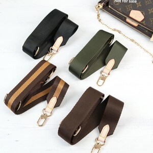 May include: Various replacement bag straps in black, olive green, and brown with gold-tone hardware. One strap has brown and tan stripes. The bag in the image is not for sale.