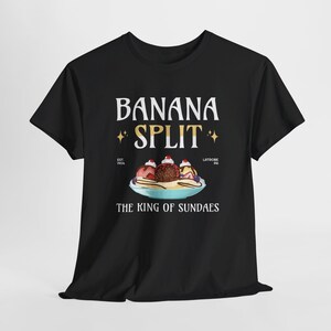 Könnte beinhalten: Schwarzes T-Shirt mit einem Aufdruck eines Bananensplit-Eisbechers. Der Text lautet "Banana Split, The King of Sundaes, Est. 1904, Latrobe, PA".